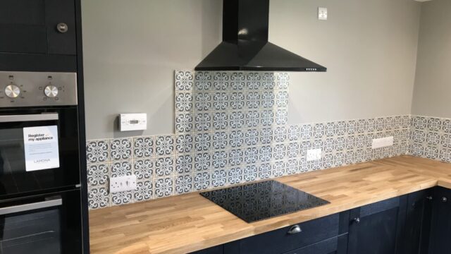 Professional tiling services in a modern kitchen with ceramic tiles on the floor and backsplash.